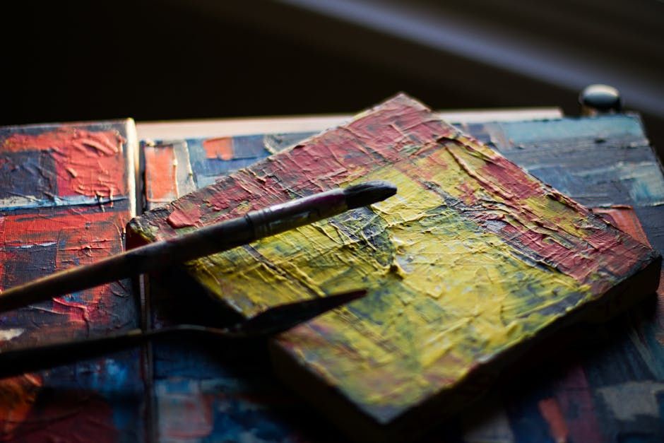Close-up of textured abstract painting with brushes showcasing vibrant colors and creative process.